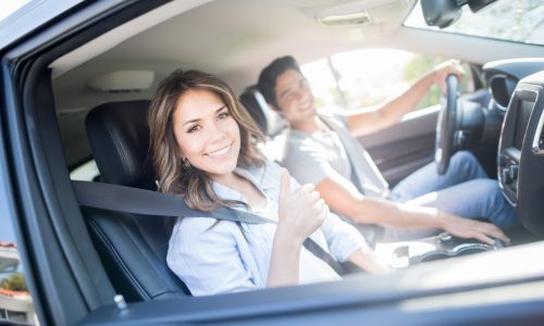 Happy couple going on a road trip and showing thumbs up