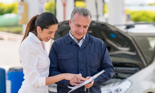 Young Latin American woman at a garage talking to a mechanic about her car